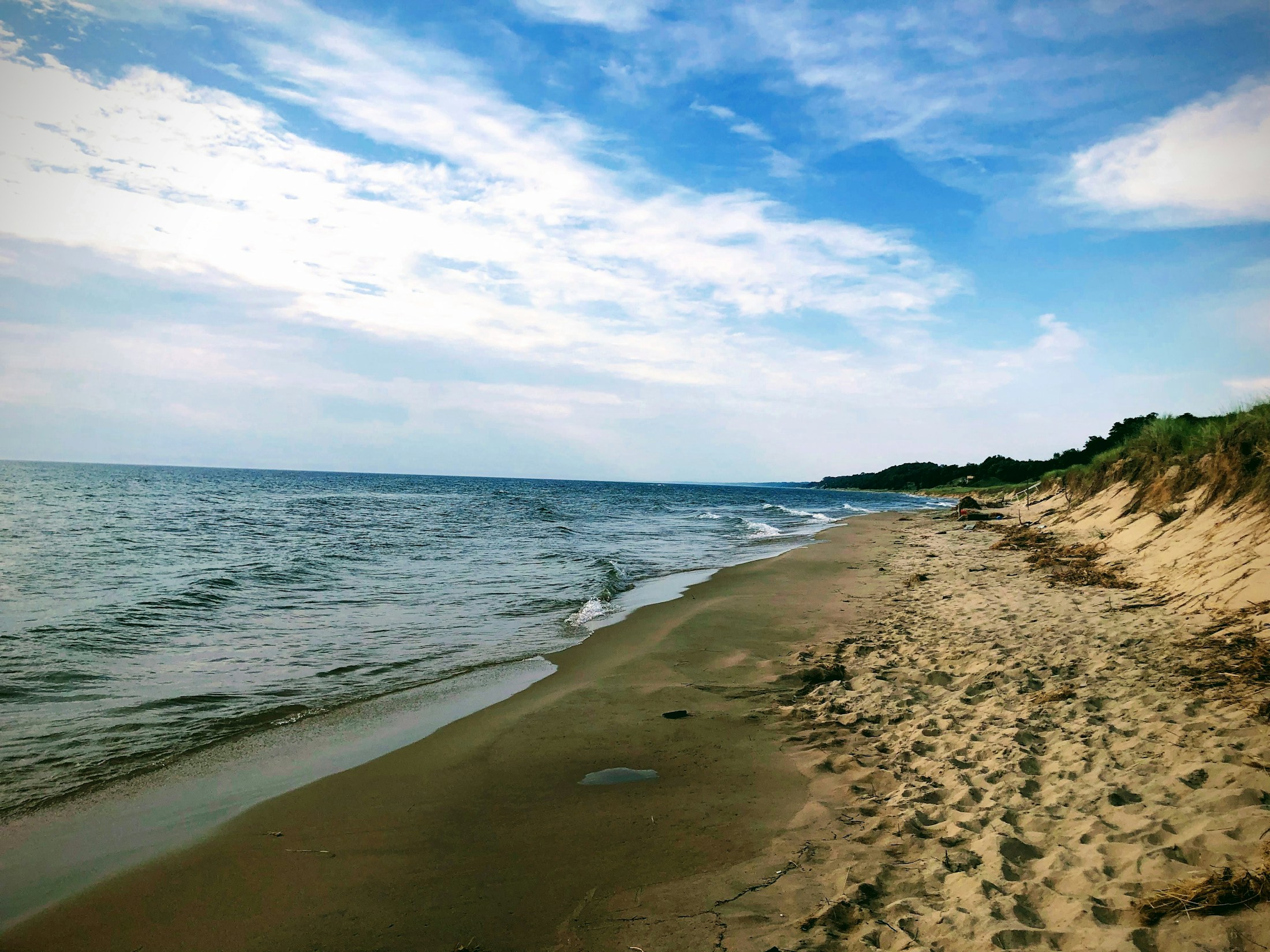 A quiet Lake Michigan shoreline with blue water, sand and open sky.